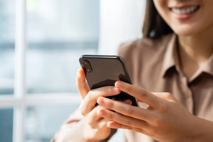 Smiling user holding smartphone and enjoying the benefits of Roamvy eSIM, from cost savings to instant activation